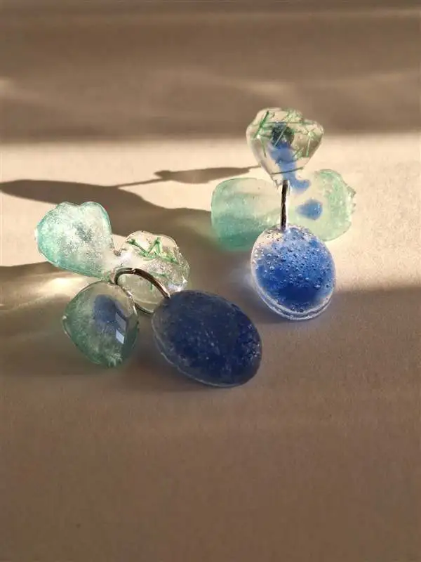 Pendientes artesanales de resina con forma de flor en tonos verde agua y azul, hechos a mano por Historias de Joyas en Barcelona