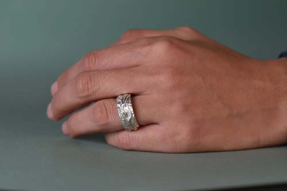 Anillo ancho de plata con textura orgánica hecho a mano, puesto en la mano