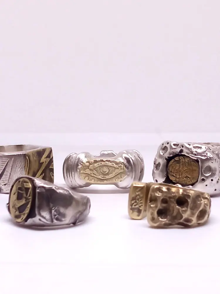 Colección de anillos artesanales de plata con detalles dorados: sellos, ojo y texturas