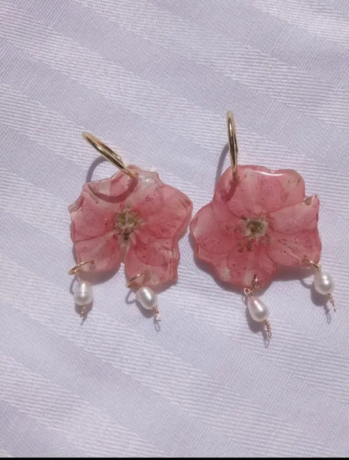 Pendientes de flor rosa con perlas hechos con resina en un taller de joyería en Barcelona