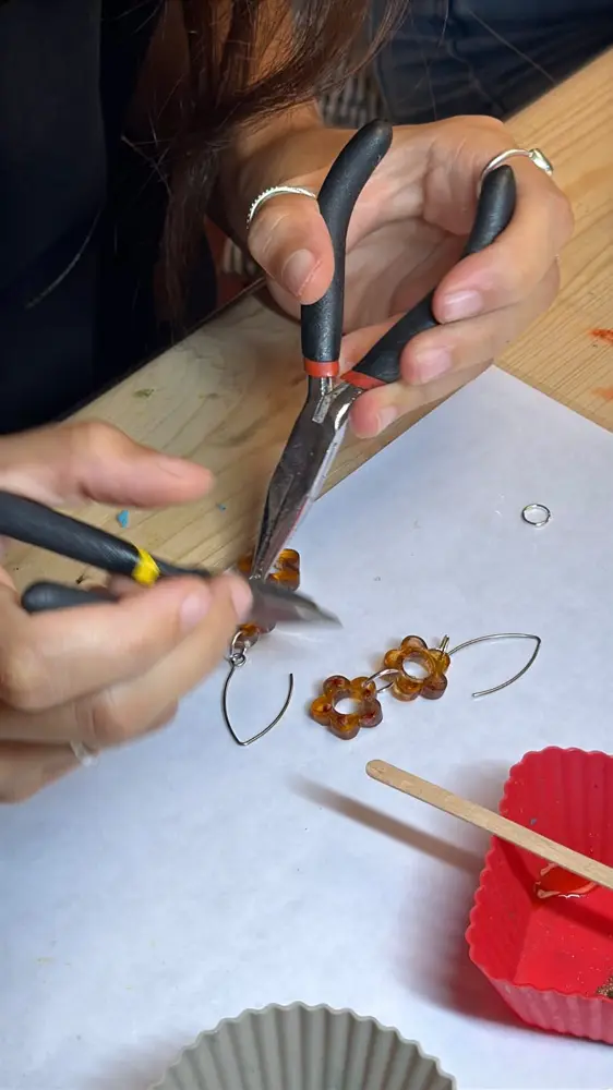 Montando unos pendientes de flor de resina durante un taller de joyería en Barcelona