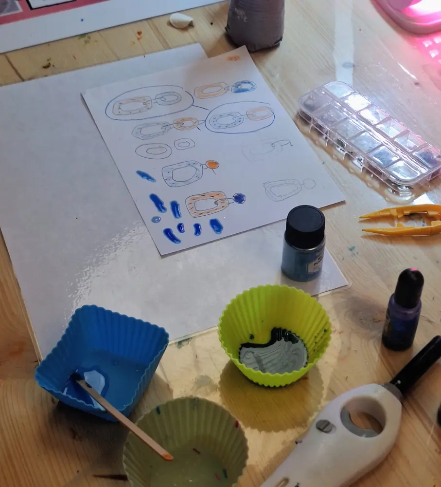 Mesa de trabajo con bocetos de joyas, pigmentos y moldes de resina de Historias de Joyas